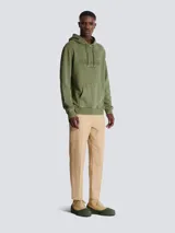 Hoodie de algodón color verde oliva con efecto vintage, presenta el logo de Balmain Paris bordado en el pecho, capucha con cordones ajustables y bolsillo tipo canguro frontal.