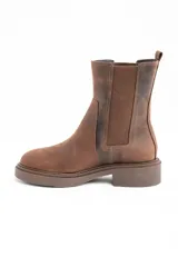 Bota tipo Chelsea de caña media, confeccionada en cuero legítimo color marrón con acabado mate. Presenta paneles laterales elásticos al tono y una suela de goma robusta con plataforma baja.