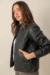 Campera de cuero negro estilo capitoneada, con diseño acolchado de rombos, cuello camisero, cierre frontal con botones a presión y bolsillos laterales.
