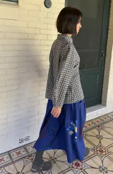 Sobrecamisa de paño con estampado de cuadros vichy en blanco y negro, de corte entallado, cuello clásico, cierre frontal con broches metálicos y mangas abullonadas.