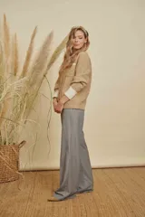 Saco de punto texturizado en color beige, con diseño de cuello redondo, cierre frontal y detalles en contraste de color blanco en los puños y en un bolsillo frontal.