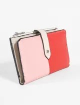 Billetera tricolor de cuero vegano con diseño de bloques de color en rojo, rosado y beige claro. Cuenta con cierre de solapa con broche a presión y compartimento con cierre superior.