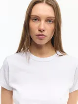 Remera básica de manga corta y cuello redondo, de corte ajustado y largo a la primera cadera, confeccionada en jersey de algodón.