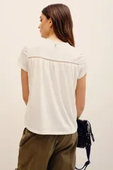 Remera blanca de manga corta, con canesú superior de broderie y detalles ajurados.