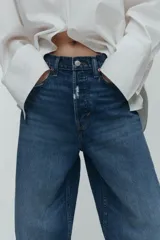 Jean tobillero de cinco bolsillos en denim de algodón rígido, con piernas de volumen curvo, corte estándar y tiro alto con cierre de botones.