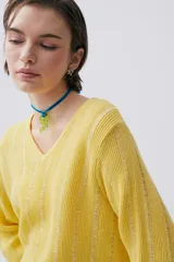Sweater amarillo tejido con lurex, escote en V y mangas largas.