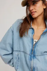Campera bomber oversize de denim suave, color azul claro con efecto gastado, cierre frontal metálico y elástico en puños y cintura.