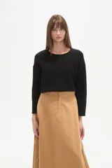 Sweater negro liso, holgado, con cuello a la base y broches decorativos en el lateral.