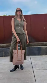 Bolso tipo tote bag de símil cuero color rosa pálido, con asas dobles y detalles de costura en color beige claro. Presenta un bolsillo frontal rectangular aplicado y herrajes metálicos.