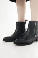 Botinetas de cuero marrón con panel elástico lateral negro y cierre metálico expuesto, con taco bajo y puntera ligeramente cuadrada.