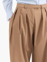 Pantalón negro de poplín asargado, corte holgado y tiro alto con pliegues frontales. Presenta un cruce en la cintura que genera un cinturón con gancho.