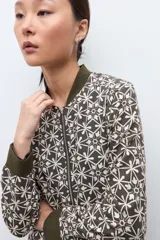 Campera bomber verde oliva con estampado geométrico en blanco, cuello, puños y cintura elásticos.