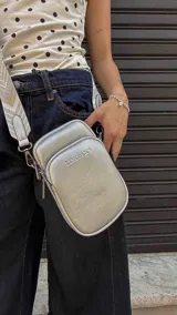 Bandolera compacta color rojo con textura de cuero, correa regulable y desmontable con diseño de rayas rojas y blancas. Cuenta con bolsillos frontales y cierre, interior forrado en tela.