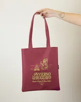 Tote bag de tela color rojo con estampado gráfico en color verde lima que representa una fogata y una persona sentada tomando una bebida caliente, acompañado por el texto 'Invierno Uruguayo'.