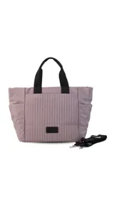 Cartera tipo tote de nylon color malva, con diseño capitoneado de líneas verticales en el frente y rombos en los laterales. Cuenta con doble asa de mano en color negro, bolsillos laterales y un parche decorativo con logo en la parte frontal.
