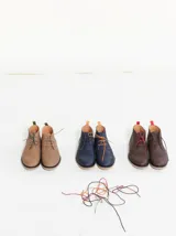 Botas tipo chukka de cuero color marrón, con cordones y suela de goma.