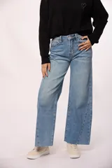 Pantalón de jean estilo wide leg con tiro alto, diseño de costuras diagonales en el frente y ruedo deshilachado.