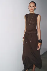 Top de tejido punto color marrón oscuro, con escote asimétrico tipo *one-shoulder* y drapeado frontal.