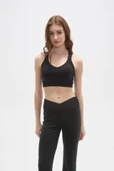 Top deportivo negro con cuello en V y espalda estilo nadadora, confeccionado en tejido elástico ajustado al cuerpo.