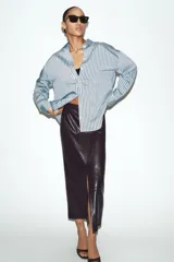Camisa de corte oversize con estampado de rayas verticales en tonos celeste y negro. Presenta cuello solapa, cierre frontal con botones y mangas largas con puños rectos.