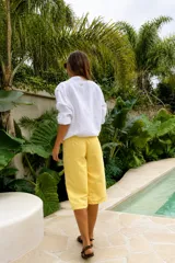 Bermuda de calce relajado y pierna amplia, color amarillo, con largo por debajo de la rodilla y cordón ajustable negro en la cintura.
