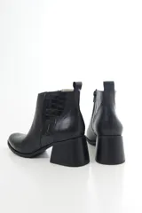 Bota corta de cuero vacuno color marrón oscuro, con taco campana y detalle de textura símil cocodrilo en la parte trasera. Cuenta con cierre lateral y tirador en el talón.