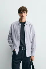 Camisa de corte regular fit confeccionada en tejido de algodón con diseño de rayas verticales. Presenta cuello abotonado, manga larga con puños abotonados y cierre frontal de botones.