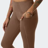 Calza deportiva New Balance Shape Shield 7/8 de tiro alto, color marrón, con paneles laterales y bolsillos integrados en la cadera.