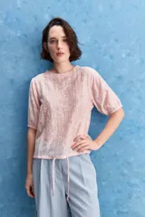 Blusa de manga corta color rosado con estampa orgánica de inspiración floral, cuello redondo y ajuste mediante lazo en el ruedo.