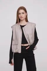 Chaleco color caqui con cierre frontal con cremallera, bolsillos con solapa y corte holgado.