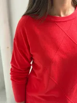 Sweater de punto color rojo con diseño de rombos en relieve, cuello redondo y mangas largas con puños acanalados.