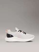 Zapatillas tipo runner Calvin Klein, de color gris con detalles en negro y coral. Presentan un diseño de malla perforada en la parte superior, cordones negros, suela chunky de EVA blanca y el logo de la marca en la lengüeta y el lateral.