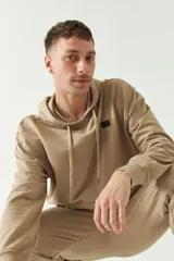 Buzo de felpa negro con capucha, cordones ajustables y bolsillo tipo canguro. Tiene puños y cintura acanalados, y logo en grifa de plástico.