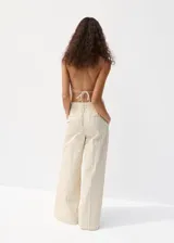Pantalón de vestir de tiro medio con diseño de rayas verticales en tono beige y crudo. Presenta pernera recta y holgada, con pinzas delanteras y bolsillos laterales.