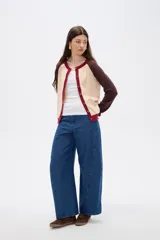 Cardigan de punto con diseño color block, presenta cuerpo en color celeste, mangas en color bordó y detalles de botones y bordes en color rosado. Posee cuello redondo y mangas largas.