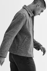 Sobrecamisa de fieltro con estampado de cuadros en tonos grises, cuello clásico, cierre bidireccional y bolsillos insertados en la parte delantera. Presenta un corte regular fit y no tiene forro.