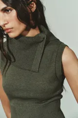 Top de punto sin mangas color verde oliva, con cuello solapa que se ajusta con un botón y terminaciones acanaladas en el cuello y el bajo.