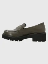Mocasín de cuero color verde oliva con textura granulada, diseño clásico con antifaz y suela track de plataforma alta en color negro.