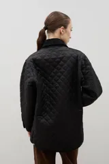 Campera acolchada de corte holgado, color blanco con diseño capitoneado en forma de rombos. Presenta cuello camisero y bordes internos con estampado floral en tonos azul y rojo, cierre frontal con botones a presión y bolsillos laterales.