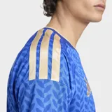 Camiseta de fútbol Adidas de manga corta para hombre, color azul con patrón geométrico en tono más oscuro. Presenta cuello en V con ribete dorado y detalles en los hombros con las tres franjas de Adidas en dorado. Incluye el escudo de la FIGC (Italia) en el pecho izquierdo y el logo de Adidas en el derecho.