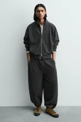 Zapatilla botín de piel con acabado serraje color verde militar, con cordones negros, pespuntes decorativos y puntera de goma negra. Suela plana negra.