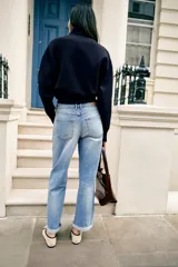 Jeans de tiro medio y corte relaxed fit, color azul con efecto deslavado, diseño de cinco bolsillos y bajo vuelto. Cuenta con cierre frontal de cremallera y botón metálico.