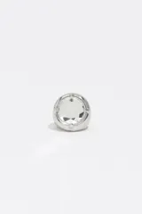 Anillo de diseño minimalista con cuerpo metálico plateado y un cristal central transparente engastado.