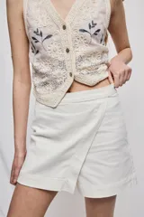 Short cruzado de tiro medio con diseño frontal tipo falda, color negro, de líneas simples y calce cómodo.