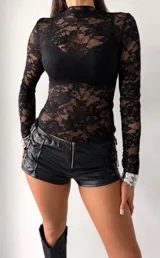Remera de encaje negro con cuello alto y mangas largas, diseñada con un ajuste al cuerpo.