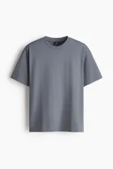 Remera gris de corte relajado, confeccionada en punto liviano con cuello redondo ribeteado, hombros caídos y mangas cortas.