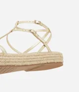 Sandalia plana tipo flatform de color dorado, con tiras finas en diseño Salomé y suela con detalle de yute trenzado.