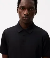 Camisa polo masculina de manga corta, confeccionada en tejido técnico de poliamida con elastano. Presenta cuello inglés con tapeta de botones y diseño liso, ofreciendo propiedades de secado rápido, elasticidad y confort térmico.