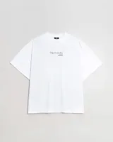 Remera de algodón blanca, corte oversize, con cuello redondo y manga corta. Presenta un pequeño estampado centrado en el pecho con texto en cursiva.