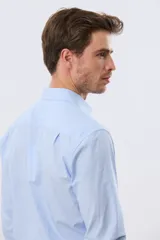 Camisa de vestir celeste rayada de manga larga, con cuello camisero, bolsillo ojal en el pecho y cierre frontal con botones.